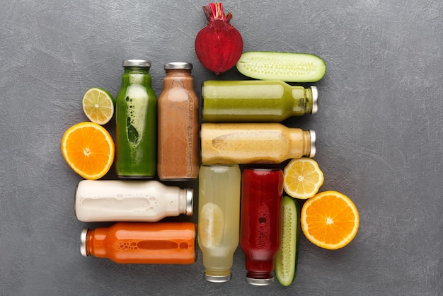 Cibo salutare. Assortimento di frullati detox di frutta e verdura in bottiglie di vetro con ingredienti su sfondo grigio, spazio copia, vista dall'alto