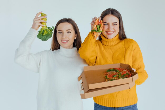 Cibo salutare. Una donna tiene in mano una pizza e l'altra un broccolo