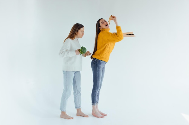 Cibo salutare. Una donna tiene in mano una pizza e l'altra un broccolo