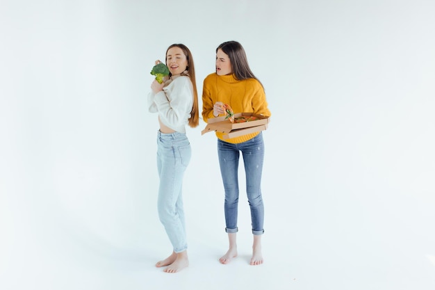 Cibo salutare. Una donna tiene in mano una pizza e l'altra un broccolo