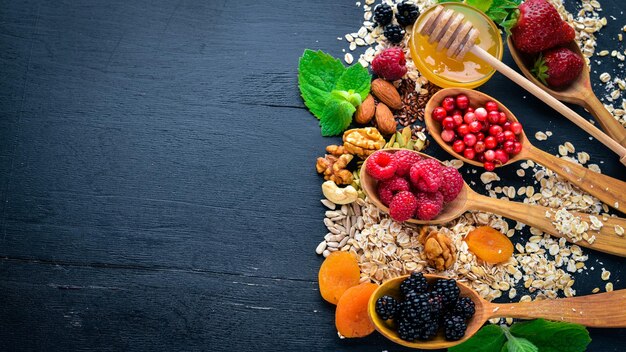 Cibo sano Bacche selvatiche fresche noci di rame farina d'avena frutta secca e semi Su uno sfondo di legno Vista dall'alto Spazio libero per il testo