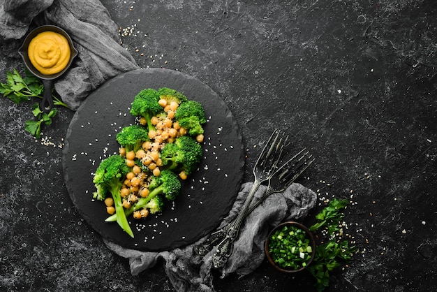 Cibo sano Broccoli alla griglia, ceci e sesamo su una lastra di pietra nera Vista dall'alto Spazio libero per il testo