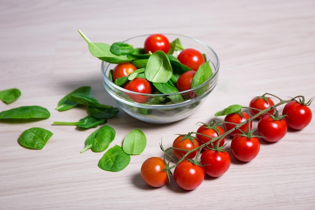 Cibo sano concetto - insalata con spinaci e pomodori su tavola di legno sullo sfondo