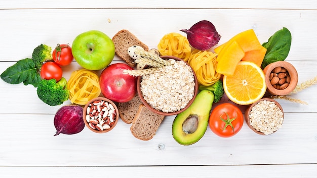 Cibo sano contenente carboidrati pane pasta avocado farina zucca broccoli fagioli spinaci su sfondo bianco Vista dall'alto Spazio libero per la copia