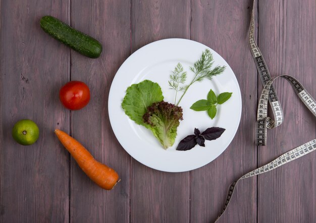 Cibo sano e dieta vegetariana concetto misura nastro piatto bianco con foglia di insalata cetriolo pomodoro e altre verdure