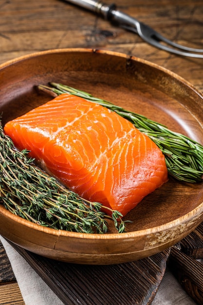 Cibo sano - filetto di salmone fresco con erbe aromatiche. Fondo in legno. Vista dall'alto.