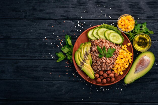 Cibo sano Grano saraceno avocado cetriolo mais e nocciola Su uno sfondo di legno Vista dall'alto Spazio libero per il testo