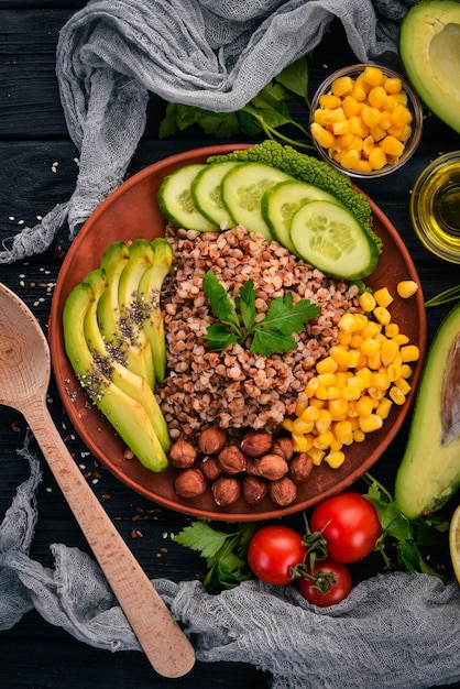 Cibo sano Grano saraceno avocado cetriolo mais e nocciola Su uno sfondo di legno Vista dall'alto Spazio libero per il testo