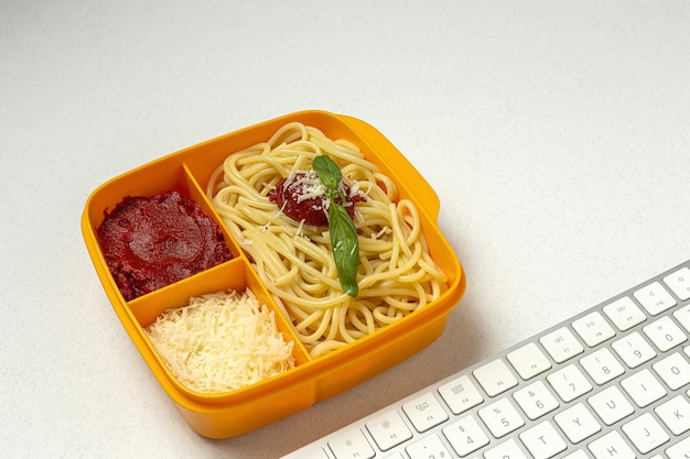 Cibo sano in contenitori di plastica pronti da mangiare con spaghetti fatti in casa con pomodoro, formaggio e basilico sul tavolo di lavoro. Cibo italiano. Portare via.