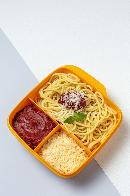 Cibo sano in contenitori di plastica pronti da mangiare con spaghetti fatti in casa con pomodoro, formaggio e basilico sul tavolo di lavoro. Cibo italiano. Portare via.