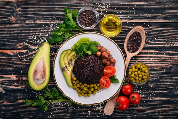 Cibo sano Riso nero avocado pomodorini piselli e nocciola Su uno sfondo di legno Vista dall'alto Spazio libero per il testo