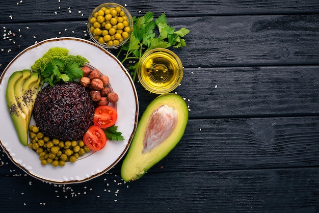 Cibo sano Riso nero avocado pomodorini piselli e nocciola Su uno sfondo di legno Vista dall'alto Spazio libero per il testo