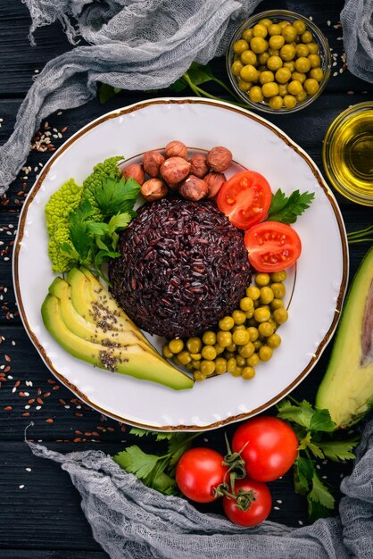 Cibo sano Riso nero avocado pomodorini piselli e nocciola Su uno sfondo di legno Vista dall'alto Spazio libero per il testo