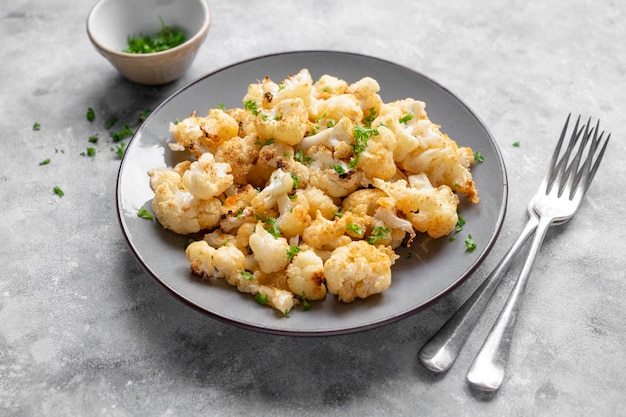 Cibo sano vegetariano. Cavolfiore al forno con formaggio, olio d'oliva e prezzemolo.