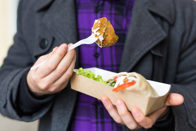 Cibo spazzatura, mangiare e concetto di stile di vita - primo piano del giovane con pasto mangia sulla strada della città