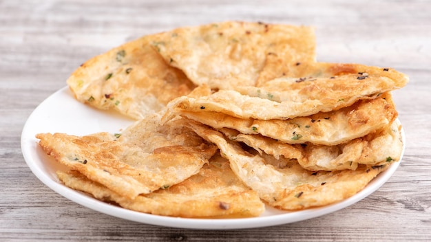 Cibo taiwanese delizioso friabile torta di scalogno frittelle su tavolo in legno luminoso sfondo spuntino tradizionale a Taiwan primo piano