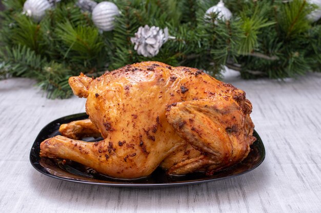 Cibo tradizionale di Natale. Pollo al forno, tacchino su un tavolo festivo con decorazioni per l'albero di Natale. Pollo con una crosta croccante marrone. Pollo fatto in casa