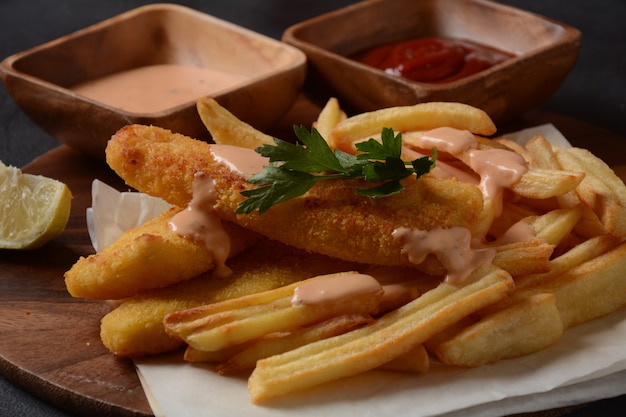 Cibo tradizionale inglese - Fish and Chips. Filetti di pesce fritti e patatine fritte croccanti serviti con ketchup e salsa tartara fatta in casa.