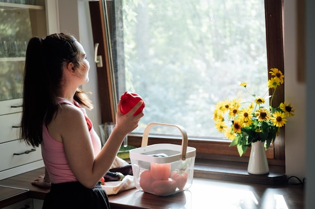 Cibo vegano e salute I vegani mangiano la giovane donna latina che tiene il peperone rosso vicino alle verdure sul tavolo