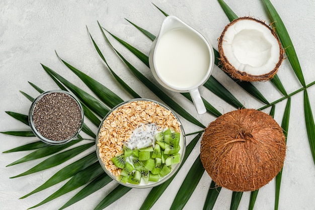 Cibo vegano. Fiocchi d'avena con latte di cocco e kiwi su sfondo grigio. Direttamente sopra.