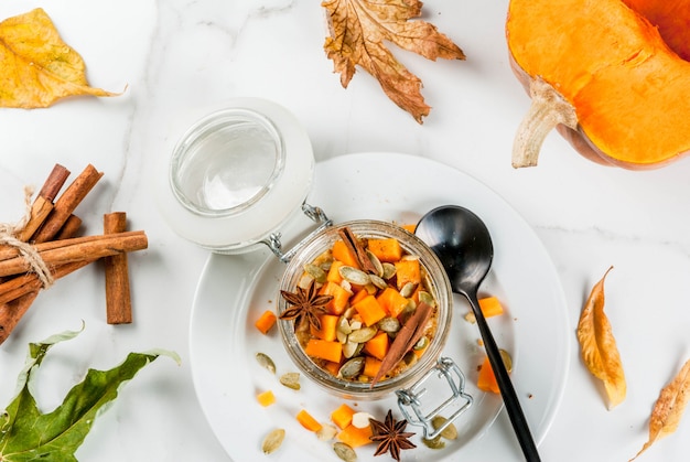 Cibo vegano sano. Colazione dietetica o merenda. Torta di zucca avena durante la notte, con zucca, yogurt, cannella, spezie. In un bicchiere, su un tavolo di marmo bianco. Copia spazio vista dall'alto