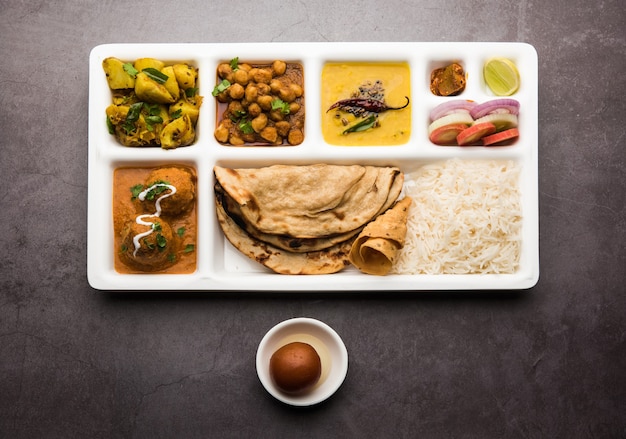 Cibo vegetariano indiano Thali o vassoio per pacchi con scomparti in cui vengono serviti Malai Kofta, chole, Dal tarka, aloo sabji secco, chapati e riso con gulab jamun dolce