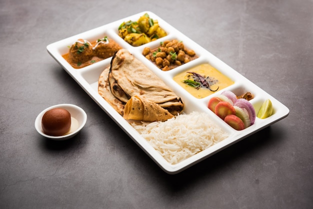 Cibo vegetariano indiano Thali o vassoio per pacchi con scomparti in cui vengono serviti Malai Kofta, chole, Dal tarka, aloo sabji secco, chapati e riso con gulab jamun dolce