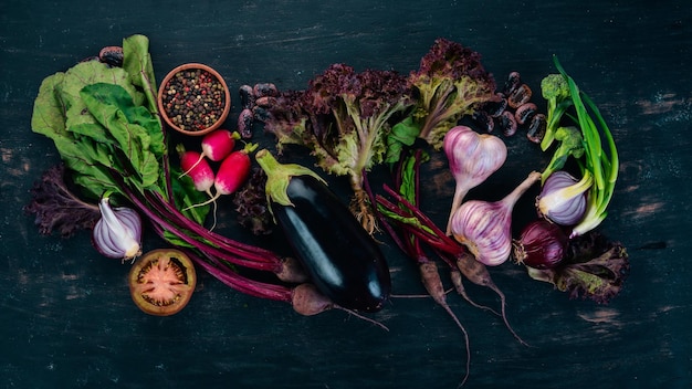 Cibo viola Verdure fresche e frutti di bosco su uno sfondo di legno Vista dall'alto Spazio di copia