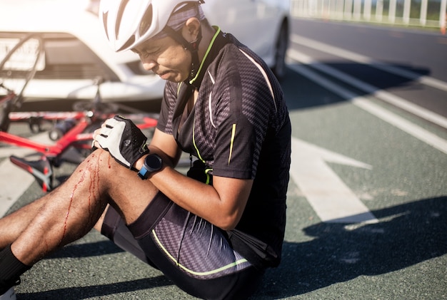 Ciclista asiatico ferito sulla bici da strada dopo incidente auto e bici.