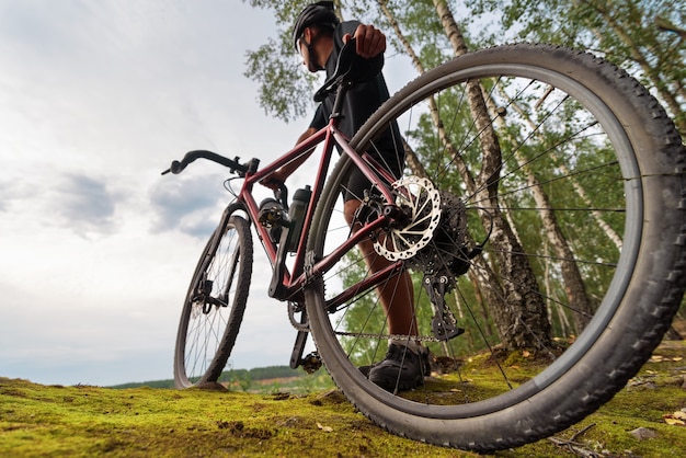 Ciclista con una bici di ghiaia che si gode lo splendido scenario mentre si rilassa dopo l'allenamento. Inquadratura dal basso.