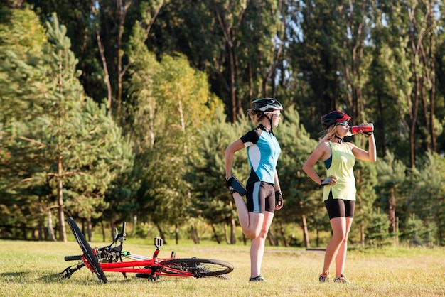 Ciclista di donne che fanno esercizi dopo aver guidato una bicicletta all'aperto nel parco