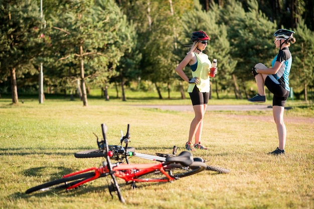 Ciclista di donne che fanno esercizi dopo aver guidato una bicicletta all'aperto nel parco