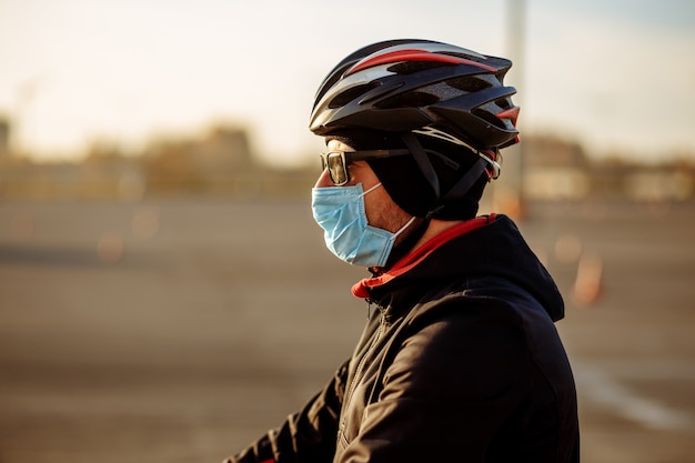 Ciclista durante la quarantena in un casco e una maschera