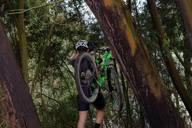 Ciclista femminile che porta la sua bici durante le escursioni in montagna