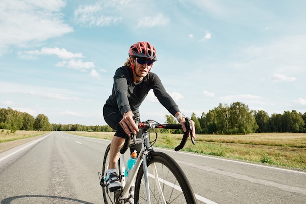 Ciclista femminile in abiti sportivi in sella a una bici da corsa sulla strada all'aperto