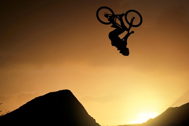 Ciclista fitness e salto acrobatico al tramonto in Colorado campagna natura montagne in fitness esercizio o allenamento Pericolo rischio sport estremi mountain bike o libertà uomo all'alba allenamento energetico