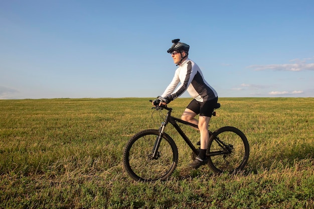 ciclista in bicicletta lungo i campi di grano alla luce del sole