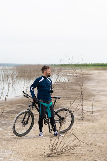 Ciclista in mountain bike su una spiaggia di sale su uno sfondo di canne e un lago