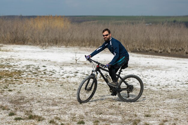 Ciclista in pantaloncini e maglia su una bici moderna con una forcella a sospensione pneumatica in piedi su una scogliera
