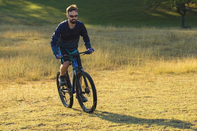 Ciclista in pantaloncini e maglia su una moderna bici hardtail in carbonio con forcella a sospensione pneumatica