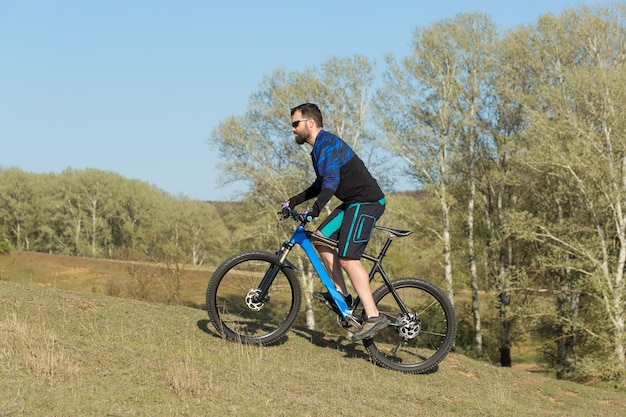 Ciclista in pantaloncini e maglia su una moderna bici hardtail in carbonio con forcella a sospensione pneumatica