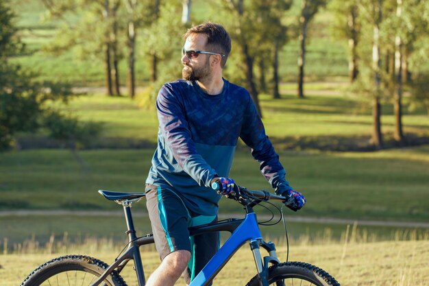 Ciclista in pantaloncini e maglia su una moderna bici hardtail in carbonio con forcella a sospensione pneumatica