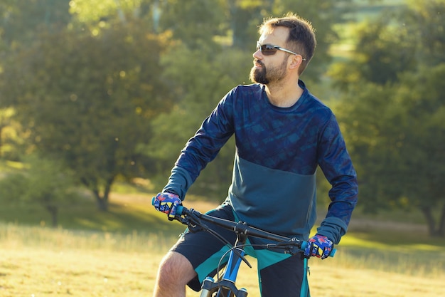 Ciclista in pantaloncini e maglia su una moderna bici hardtail in carbonio con forcella a sospensione pneumatica