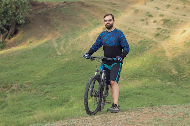 Ciclista in pantaloncini e maglia su una moderna bici hardtail in carbonio con forcella a sospensione pneumatica