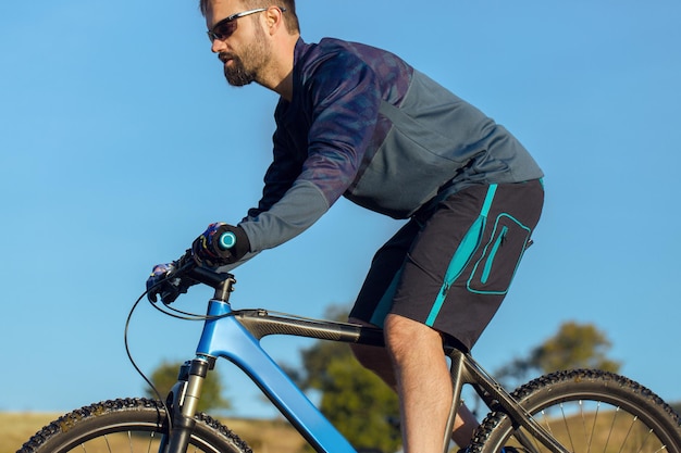 Ciclista in pantaloncini e maglia su una moderna bici hardtail in carbonio con forcella a sospensione pneumatica