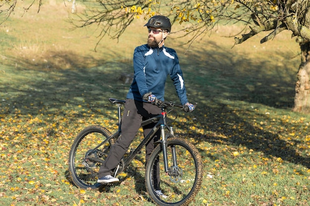 Ciclista in pantaloni e giacca in pile su una moderna bici hardtail in carbonio con forcella a sospensione pneumatica Il ragazzo in cima alla collina va in bicicletta