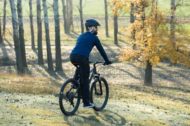 Ciclista in pantaloni e giacca in pile su una moderna bici hardtail in carbonio con forcella a sospensione pneumatica