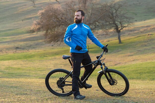 Ciclista in pantaloni e giacca in pile su una moderna bici hardtail in carbonio con forcella a sospensione pneumatica