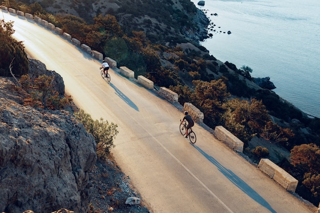 Ciclista in sella alla sua bicicletta in strada costiera al mattino