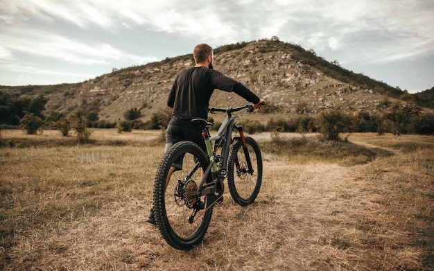 Ciclista irriconoscibile con la bicicletta che cammina nella campagna